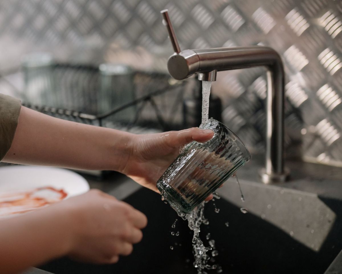 Frau spült ein Glas ab.
