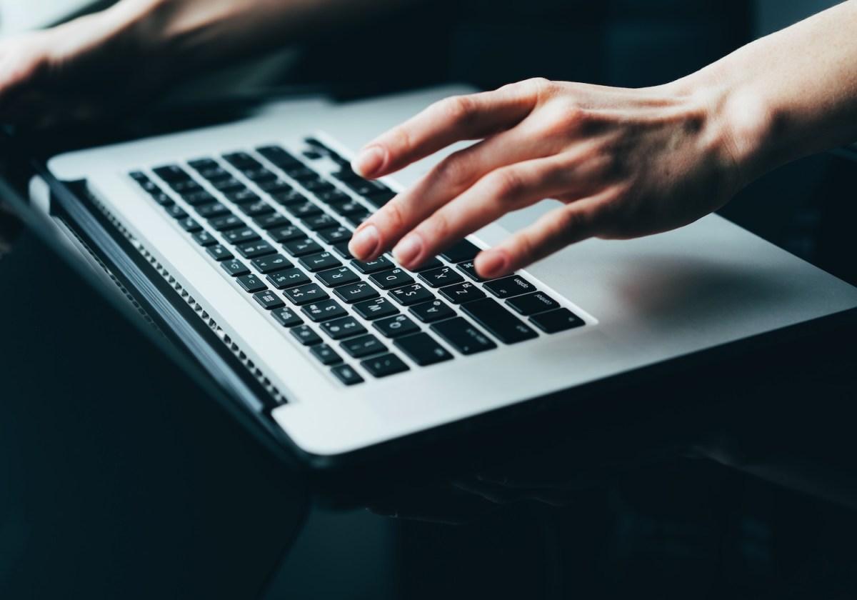 Eine Nahaufnahme einer Frauenhand, die auf einem Laptop die Tasten drückt.