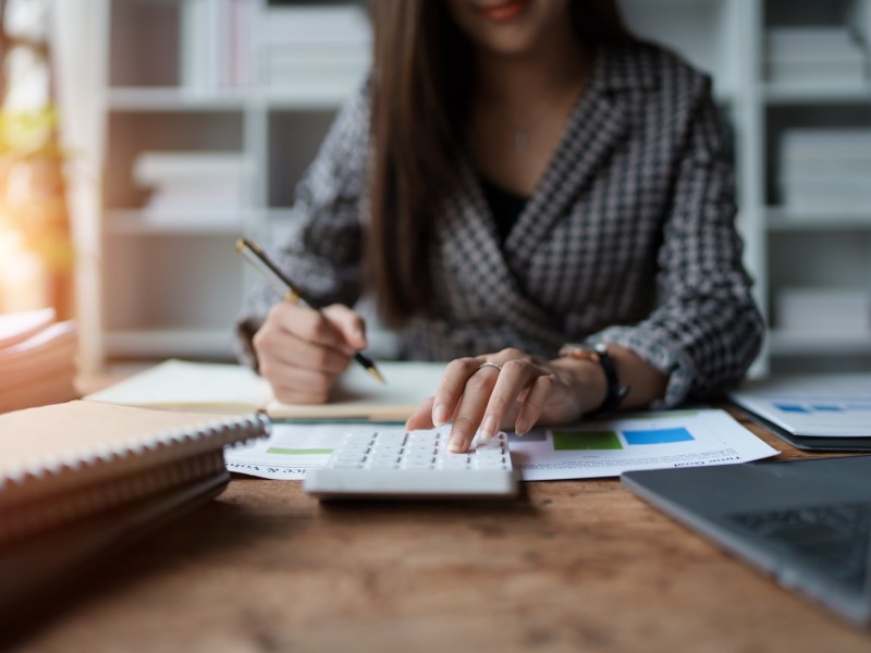 Junge Frau arbeitet zu Hause mit Finanzunterlagen.