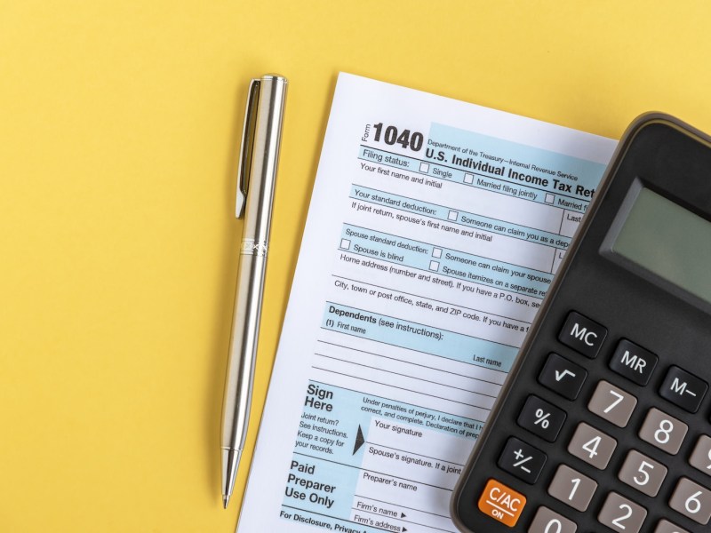 Steuerunterlagen und Taschenrechner auf gelben Hintergrund.