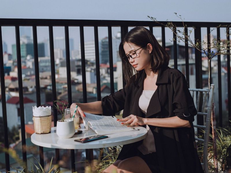 Frau sitzt auf einer Terrasse und liest ein Buch
