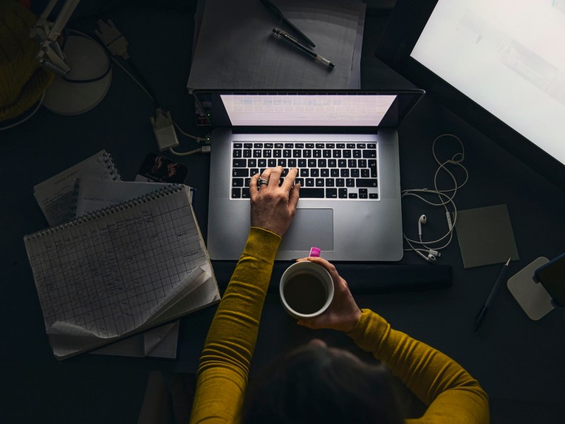 Eine Frau sitzt abends an ihrem Laptop und arbeitet.