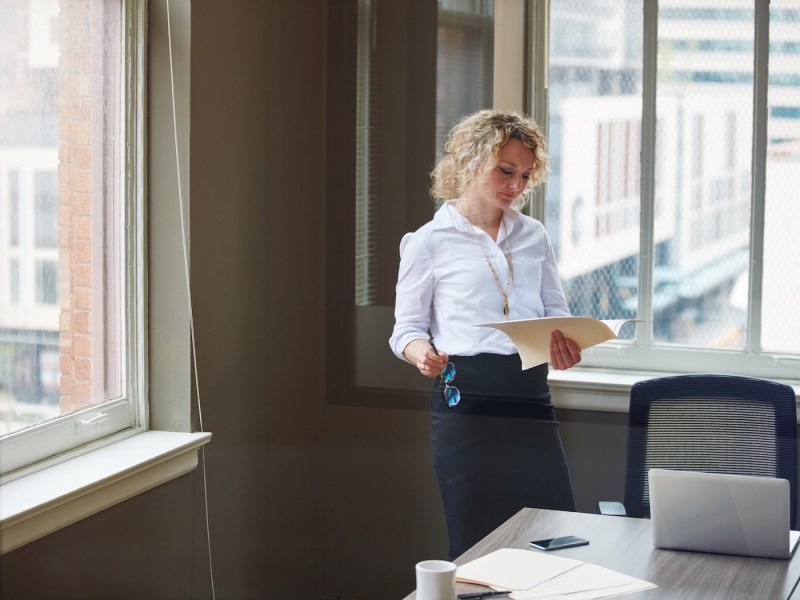 Aufnahme einer Geschäftsfrau, die in einem Büro einen Bericht liest.