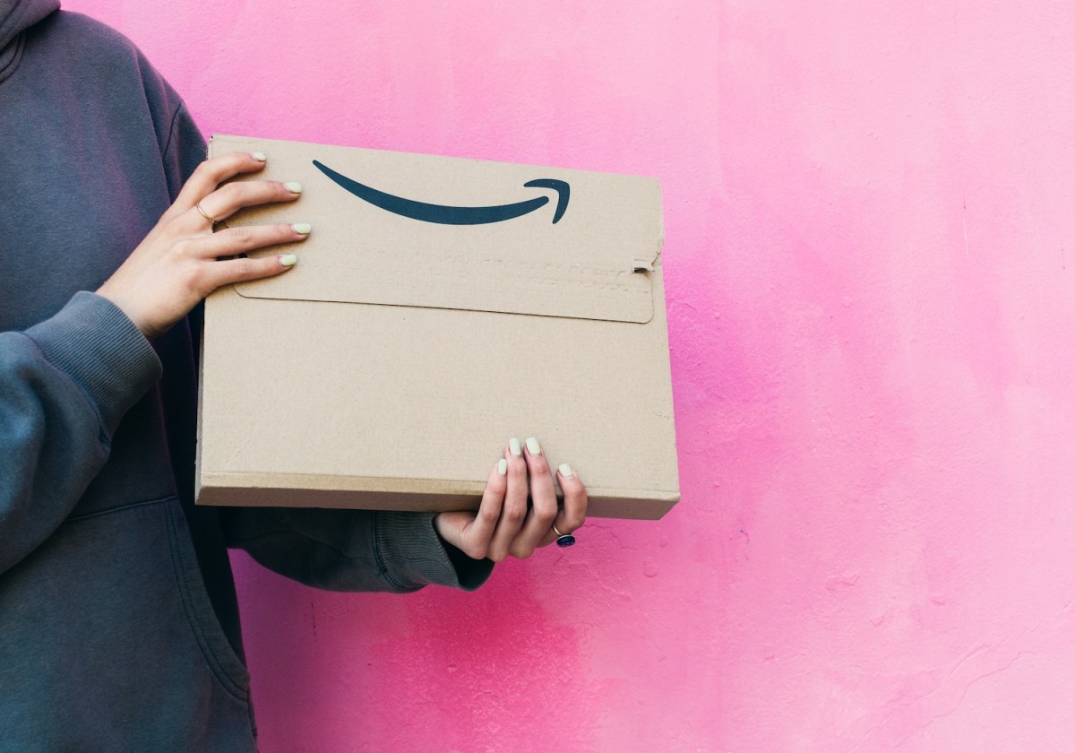Körper einer jungen Frau, die ein Amazon-Paket in der Hand hält.