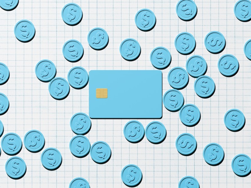 Digital generiertes Bild einer pastellblauen Kreditkarte mit Chip auf weißem Papierhintergrund mit Gittermuster, umgeben von verstreuten blauen Münzen.