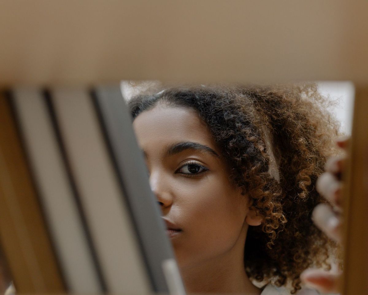 Frau schaut durch Bücherregal.