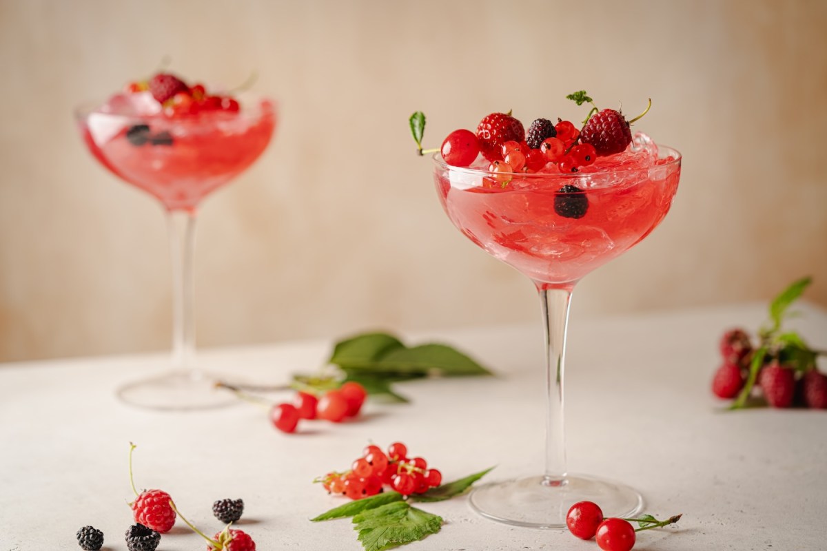 Glas Beerencocktail mit frischen Beeren auf weißem Hintergrund.