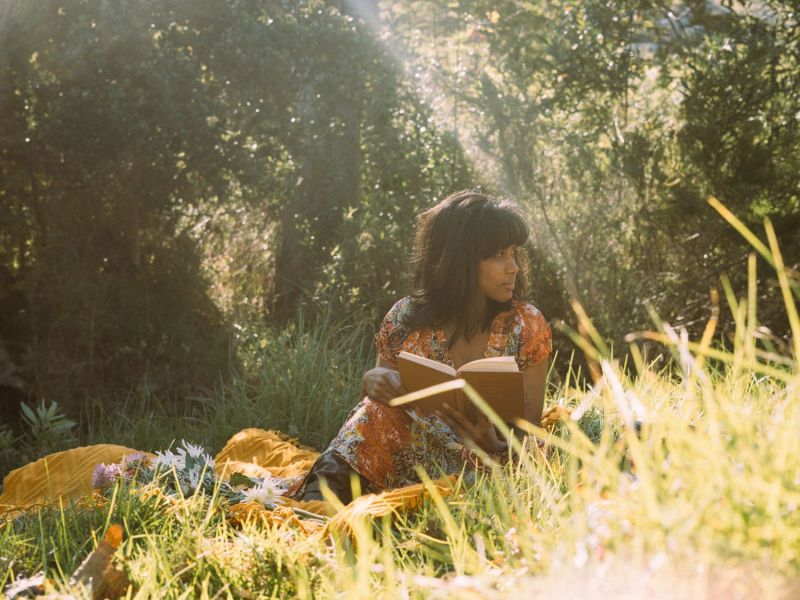 Frau sitzt im Gras und liest.