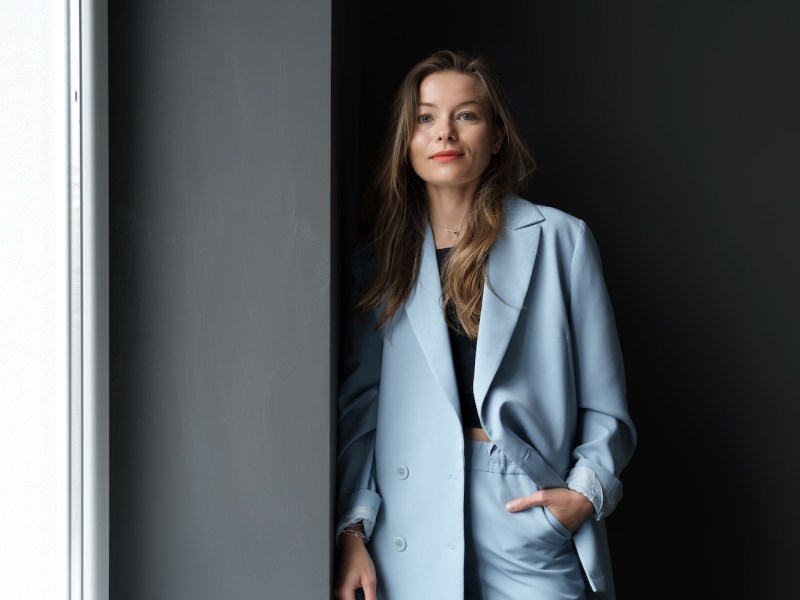 Moderne junge Geschäftsfrau trägt lässige Kleidung posiert drinnen.