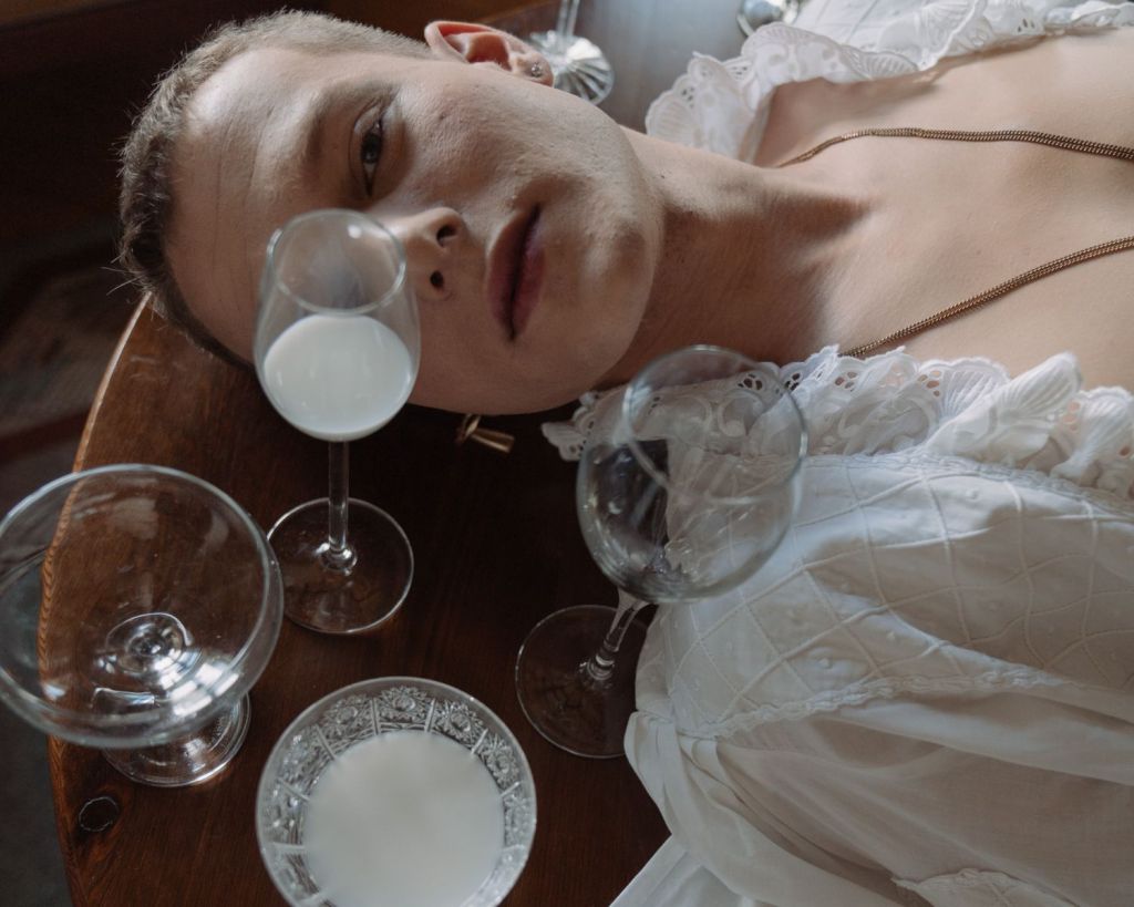 Mann liegt auf einem Tisch, umgeben von Kristallgl&auml;sern.