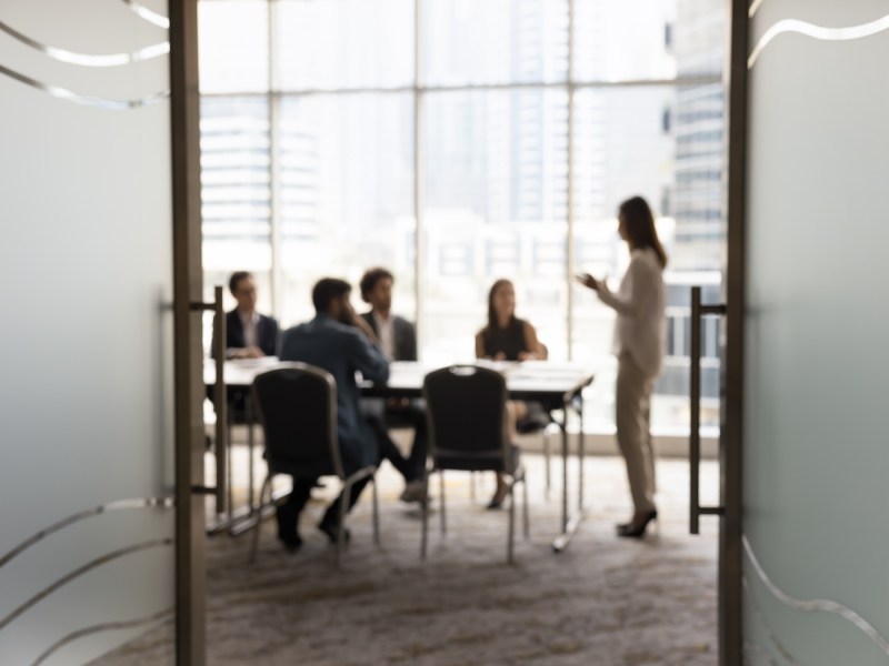 Silhouetten von Geschäftsleuten, die sich in einem Konferenzraum versammelt haben.