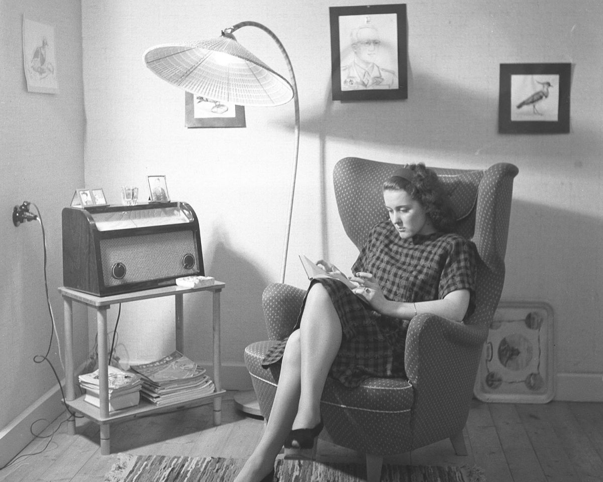 Frau sitzt auf einem Sessel und liest; in Schwarz-Weiß.