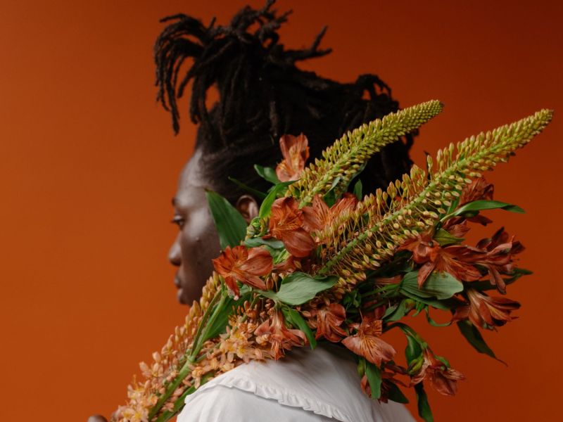 Frau hält eine Pflanze über der Schulter.