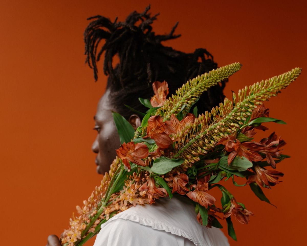 Frau hält eine Pflanze über der Schulter.