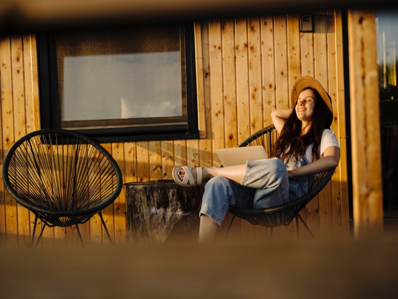 Frau benutzt Laptop während der Arbeit auf ihrer Terrasse.