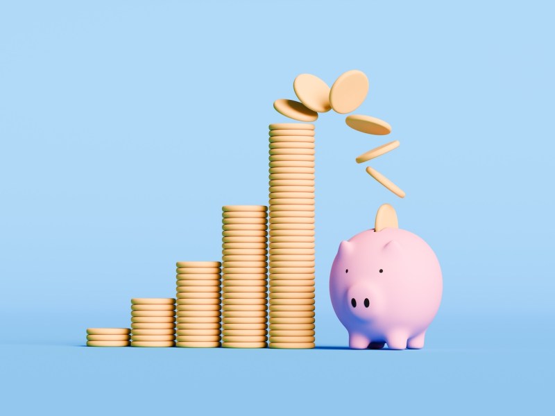 Stücke der umstürzenden Münzen fallen in ein Sparschwein.