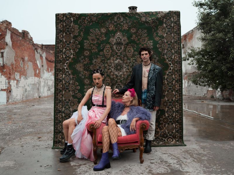 Drei Leute posieren vor einem alten Teppich.