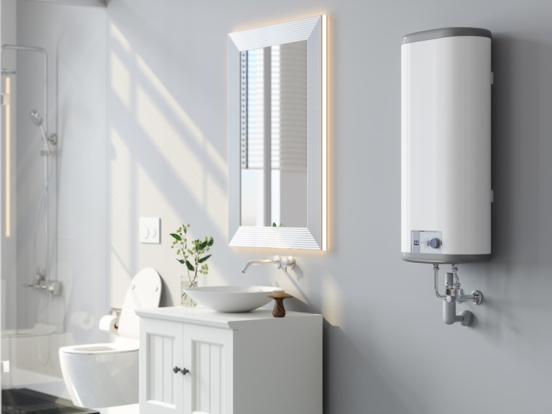 Nahaufnahme vom Durchlauferhitzer, Spiegel und weißem Schrank im modernen Badezimmer.