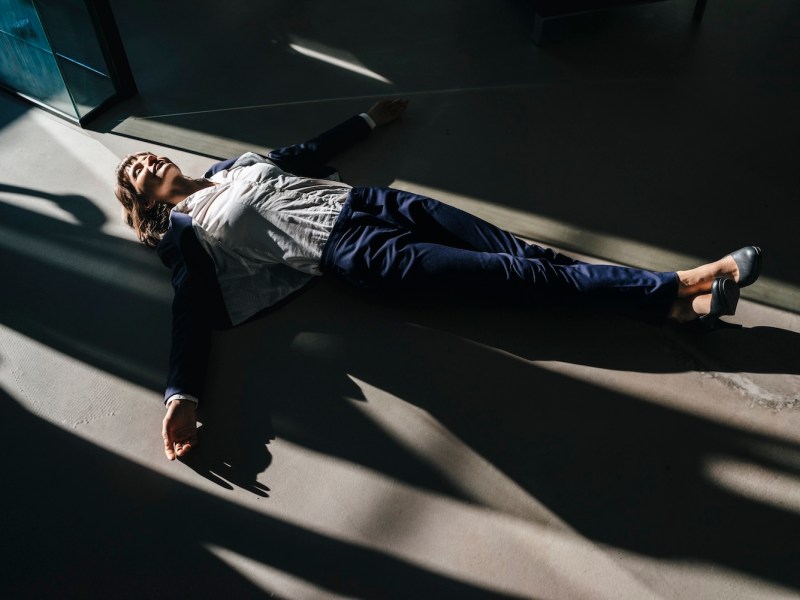 Eine Frau im Hosenanzug liegt auf dem Boden