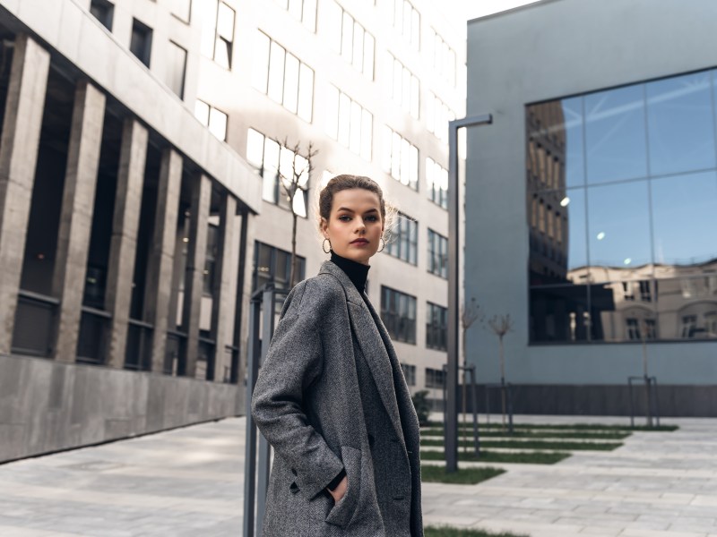 Eine selbstbewusste Frau steh vor einem Bürogebäude.