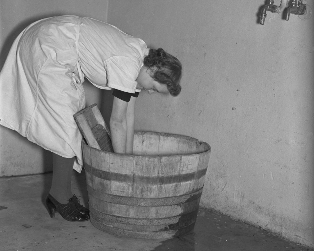 Oma wäscht Sachen in einem Fass