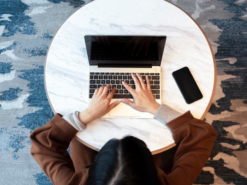 Eine Frau mit schwarzem Haar tippt auf dem Laptop.