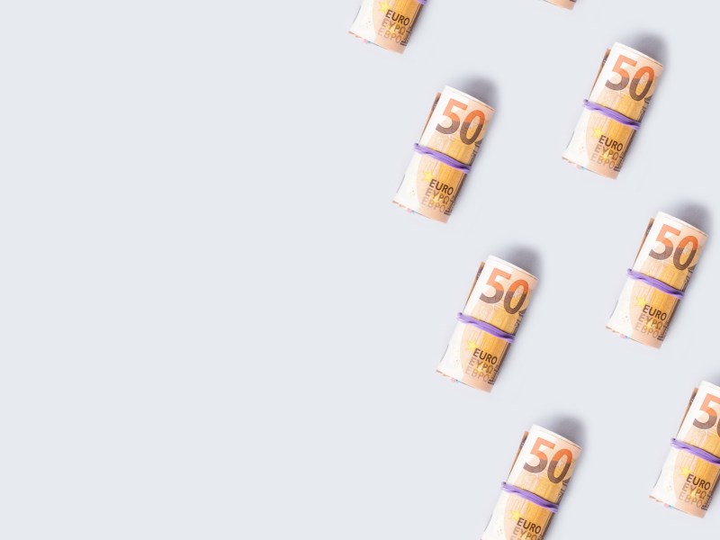 50-Euro-Banknoten rollen auf grauem Hintergrund.