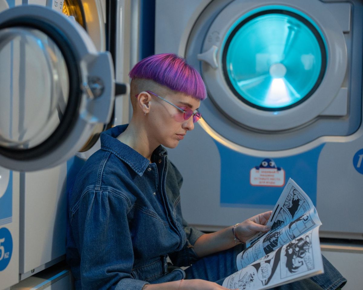 Frau liest ein Comic-Heft im Waschsalon