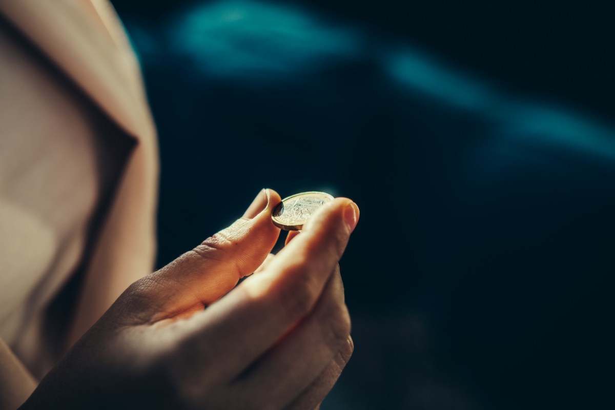Eine Frau hält eine Ein-Euro-Münze in der Hand.