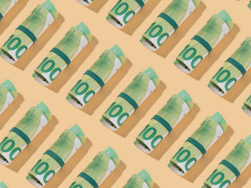 Rolle von Hundert-Euro-Scheinen auf beigen Hintergrund.