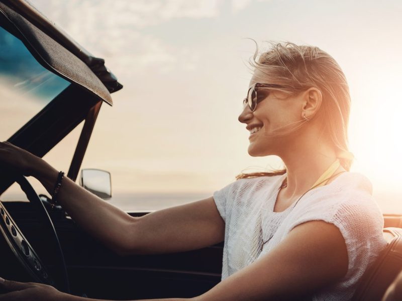 junge frau fährt im auto strasse