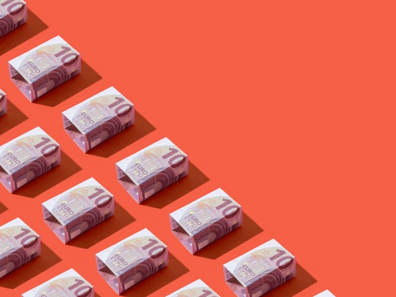 Quadratische zehn Euro-Banknoten in einer Reihe auf rotem Hintergrund.