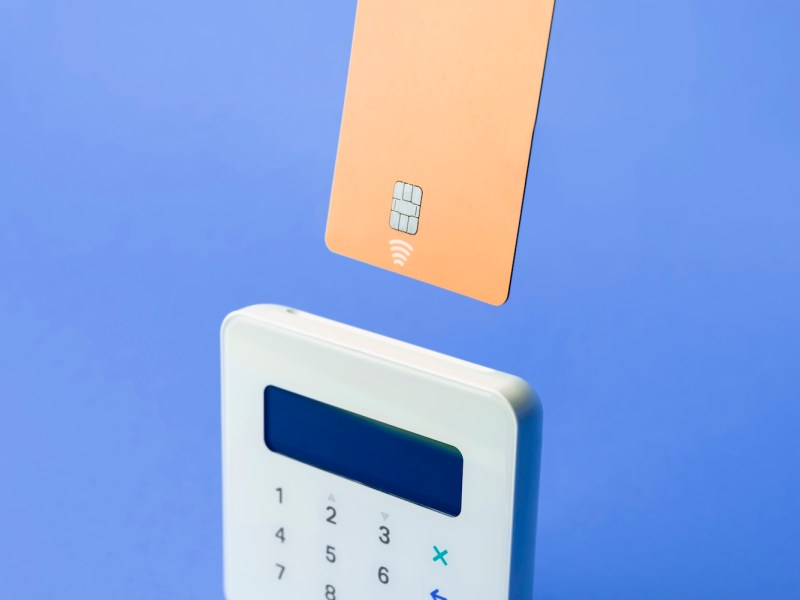 Erhöhte Ansicht des Kreditkarten-POS-Terminals auf blauem Hintergrund.