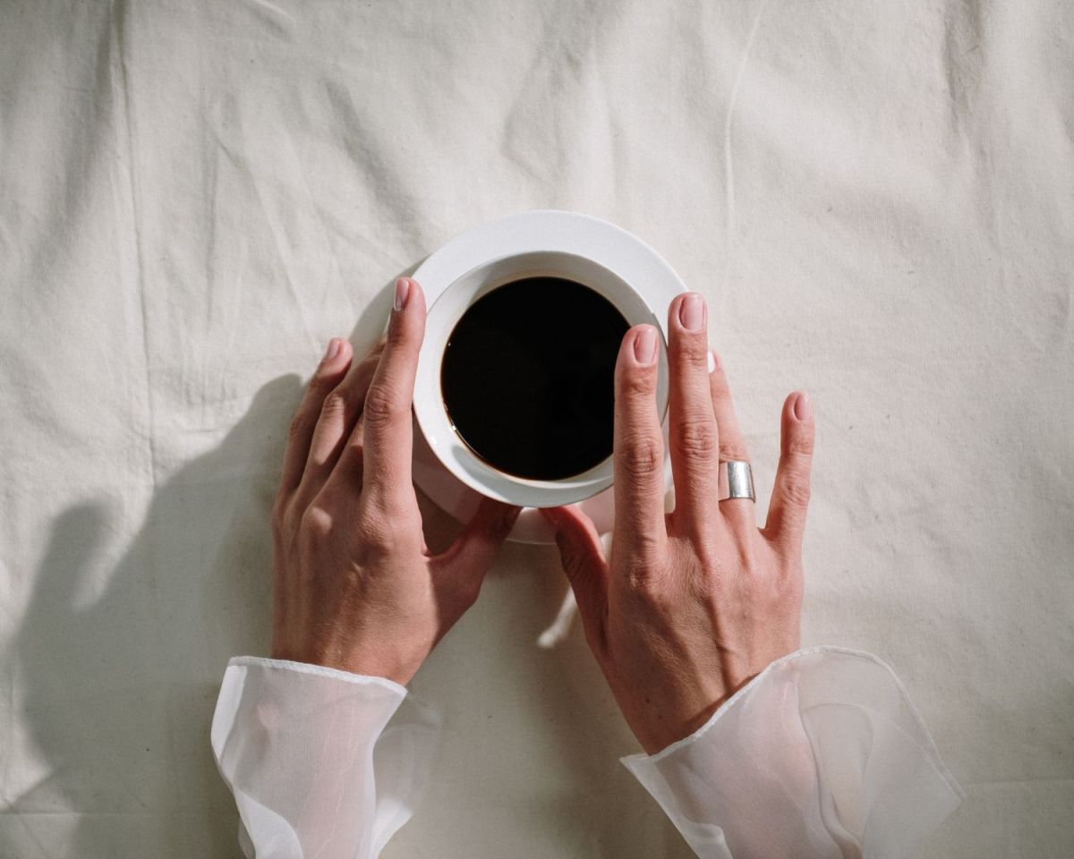 Frau hält eine Kaffeetassse in den Händen.