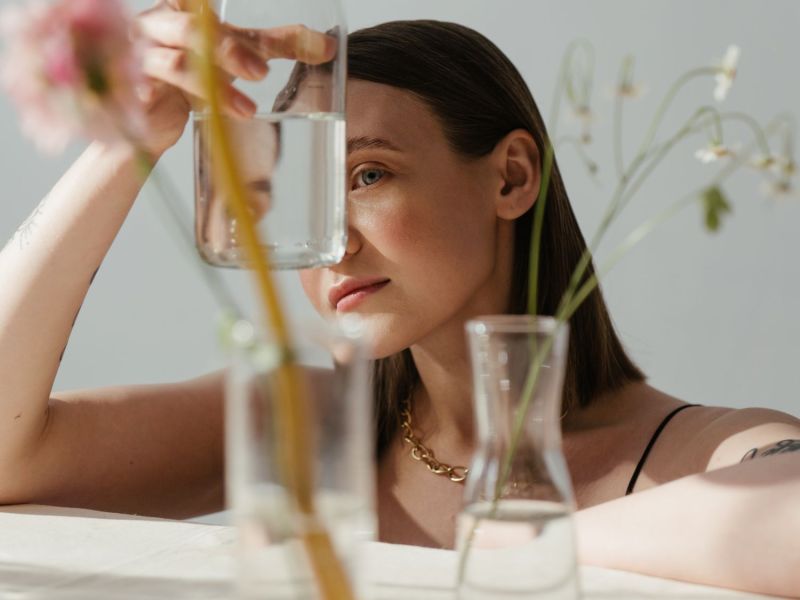 Frau schaut durch eine Blumenvase