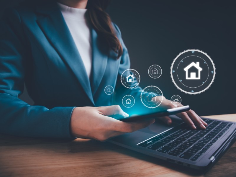 Eine Frau sitzt am Laptop. Darum erscheinen Finanzsymbole.