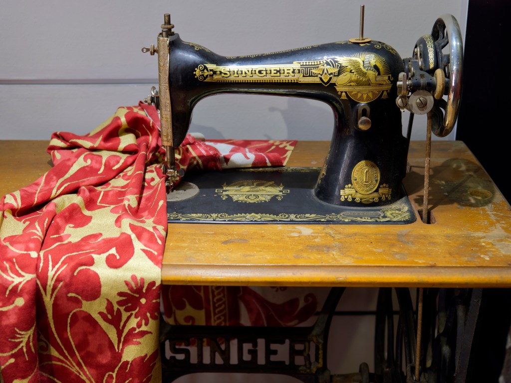Antike Singer N&auml;hmaschine steht auf einem Tisch mit Stoff