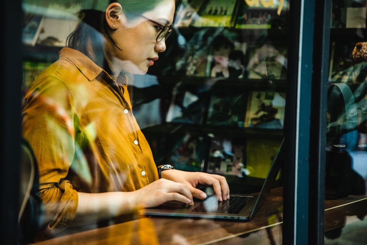 Eine Frau sitzt am Laptop und schreibt.