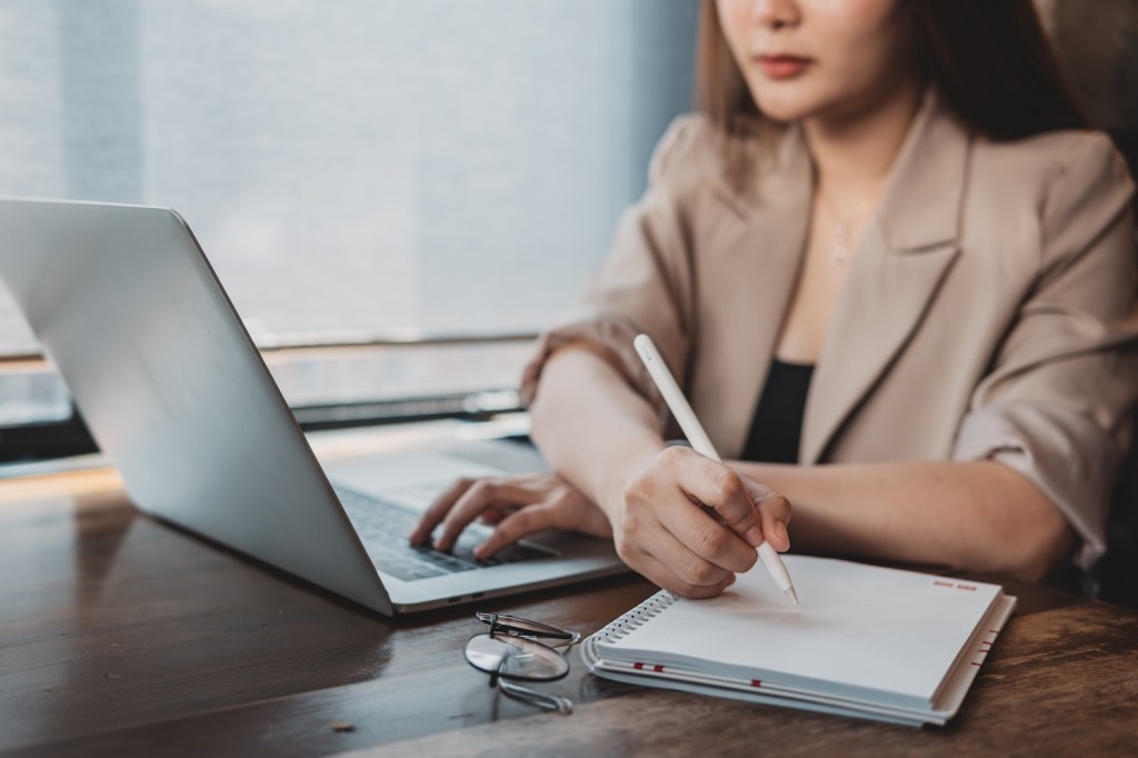 Frau arbeitet mit Laptop und Dokumenten.