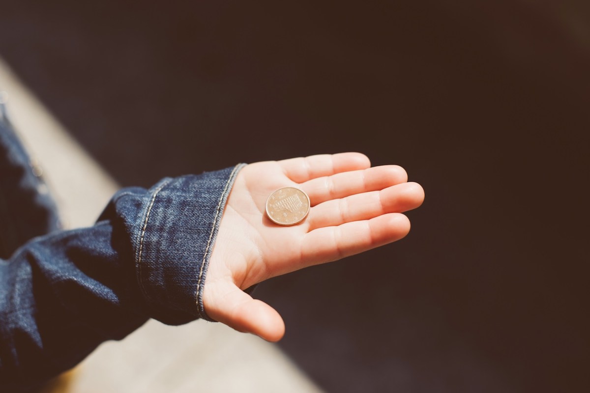 In einer Kinderhand liegt eine 5-Cent Münze.