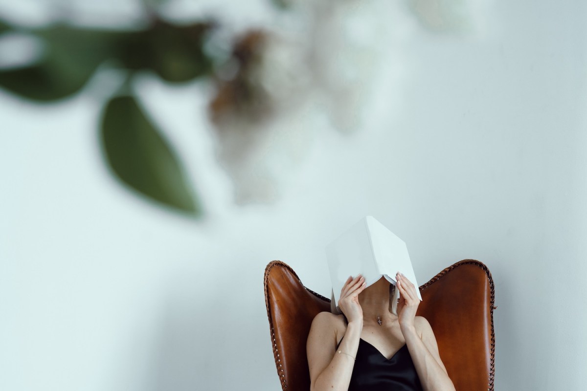 Eine Frau hält sich ein Buch vor das Gesicht.