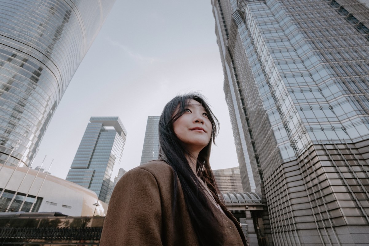 Eine Frau steht vor Hochhäusern.