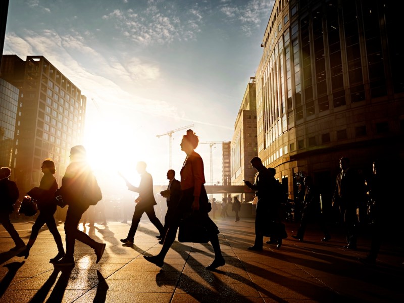 Eine Frau geht mit anderen Geschäftsleuten über die Straße.