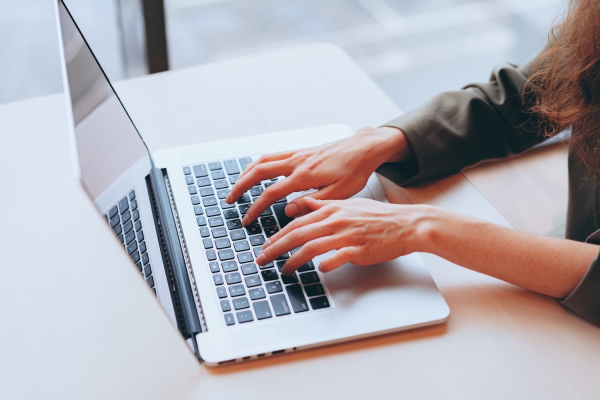 Eine Frau sitzt am Laptop und tippt.