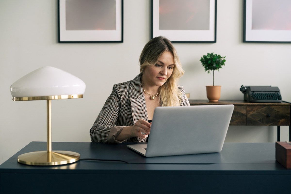 Eine blonde Frau sitzt am Laptop.
