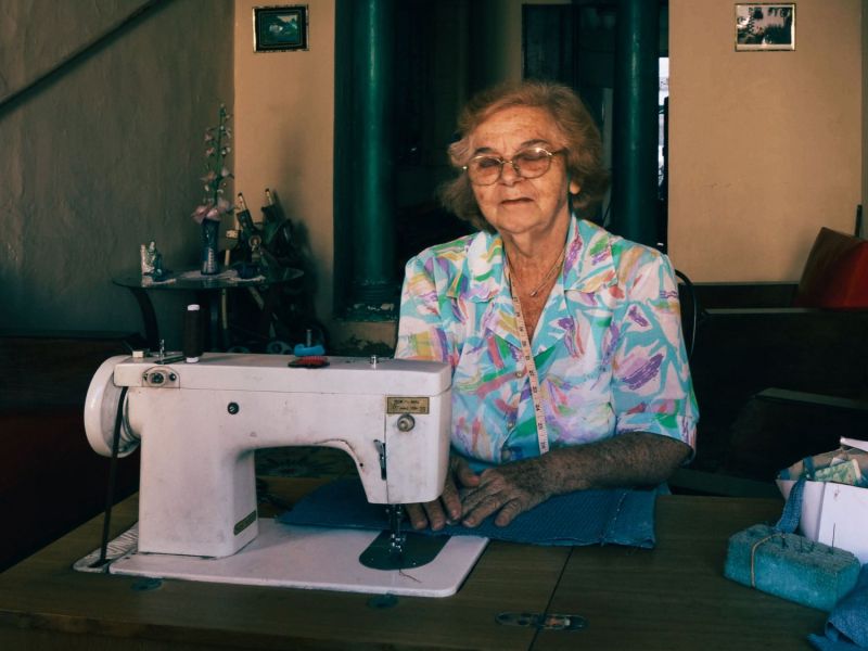 Alte Dame sitzt an einer Singer Nähmaschine