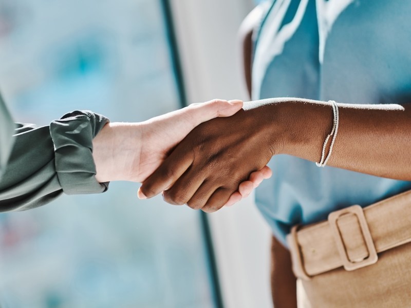 Zwei Frauen geben sich einen Handschlag.