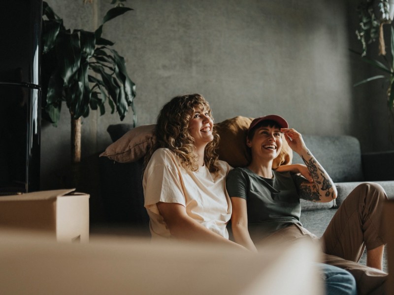 Zwei Frauen sitzen nach dem Umzug zufrieden auf dem Sofa.