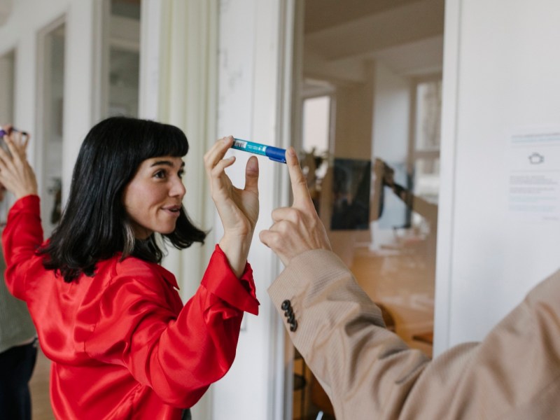 Eine Frau und ein Kollege balancieren einen Stift.
