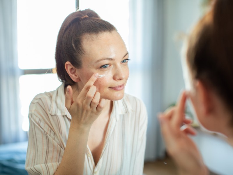 Frau trägt sich Augencreme auf